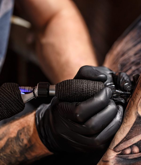 Tattoo artist creating a tattoo on a man's arm